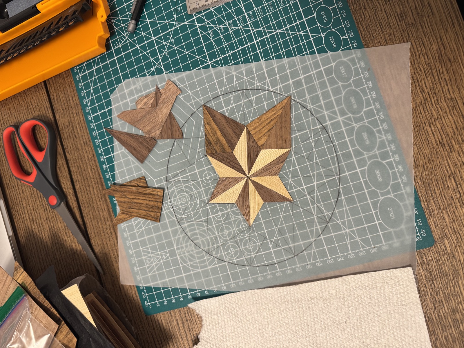 The first cut veneer pieces laid on a paper pattern beside a cutting mat