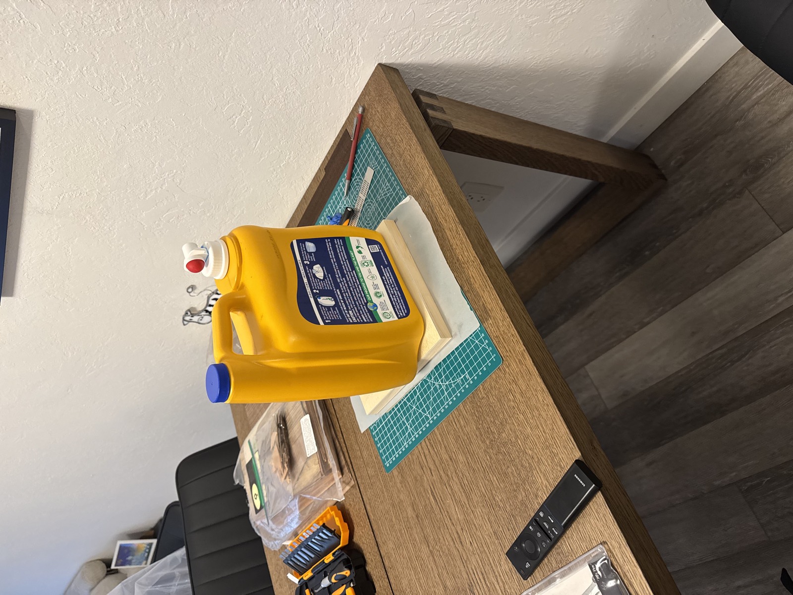 The glued panel pressed flat under a board weighted with a large jug of laundry detergent