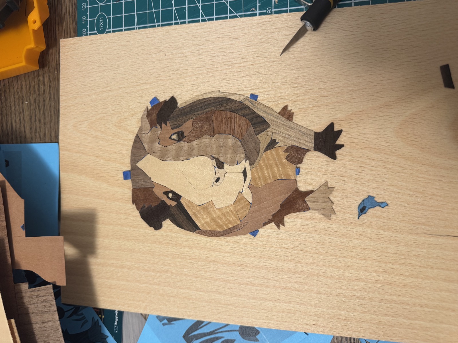 The assembled guinea pig laid out on the pale substrate panel, taped in position, with a craft knife beside it
