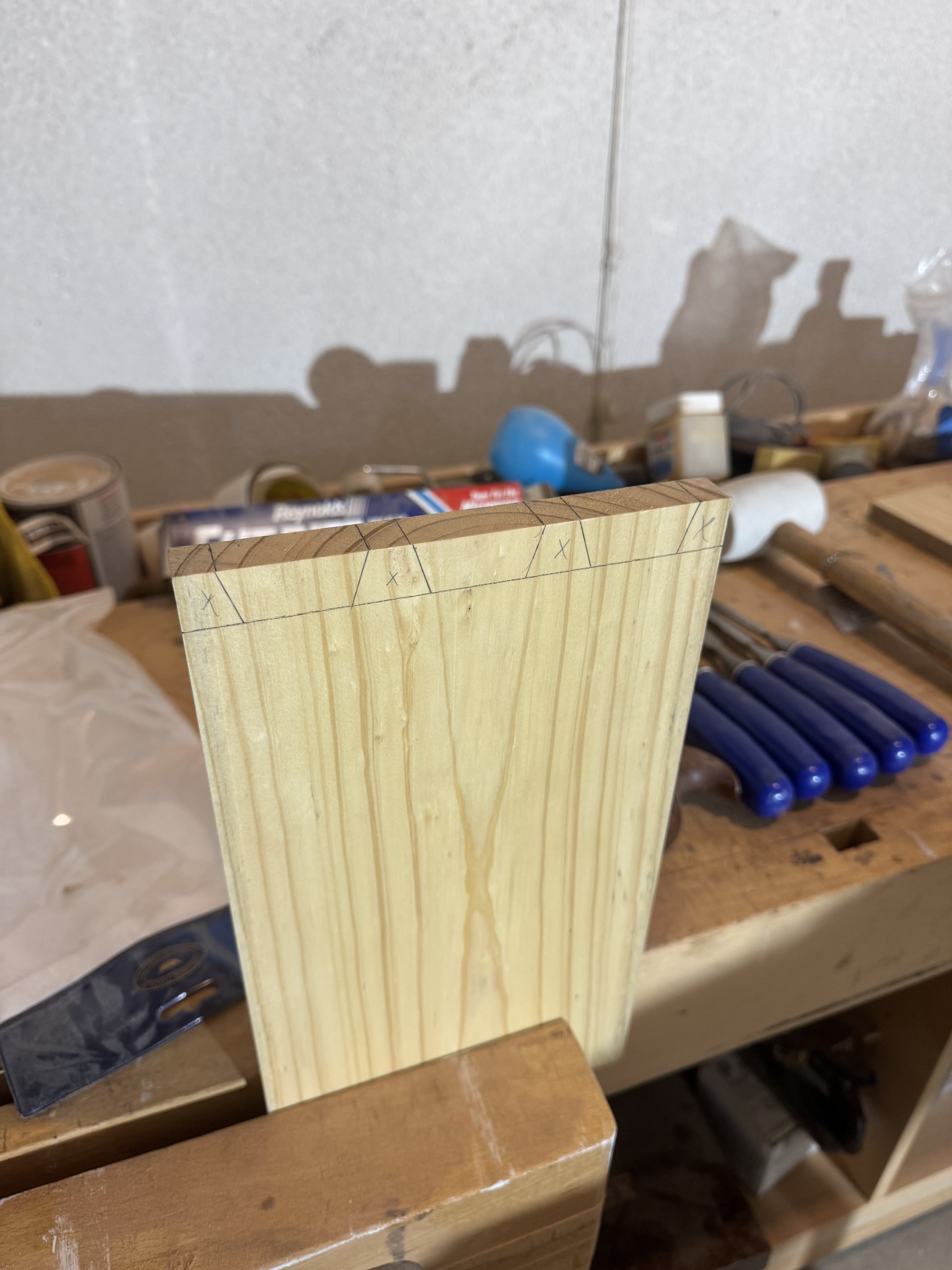 Dovetails marked out in pencil on the end of a board, with waste marked to remove