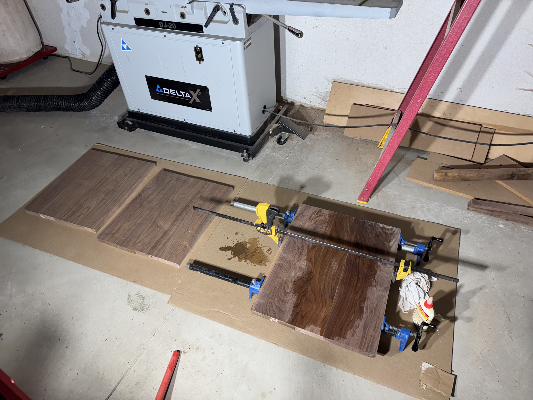 Walnut panels glued and clamped on the floor by the jointer