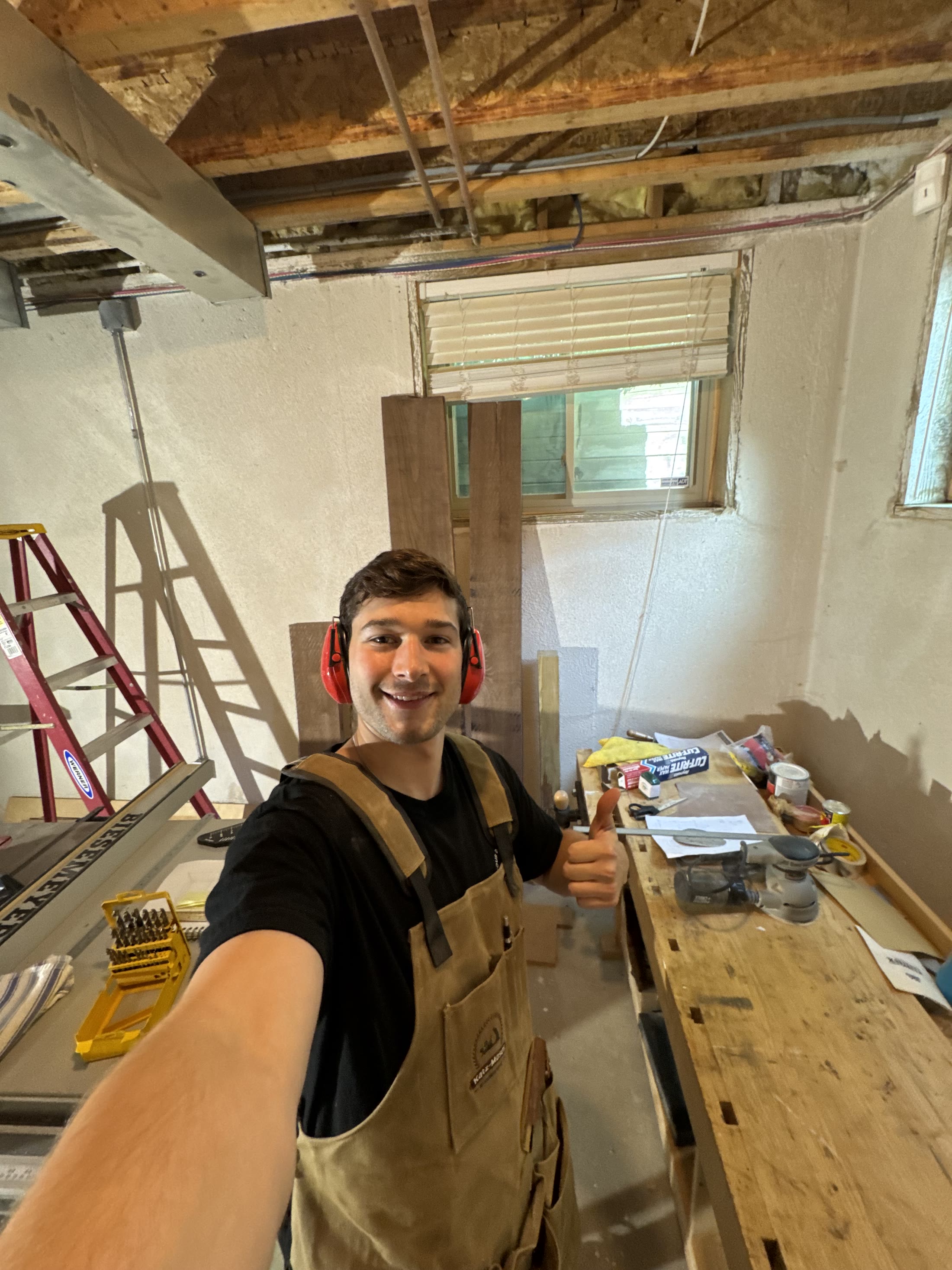 Samuel in the shop with walnut boards behind him